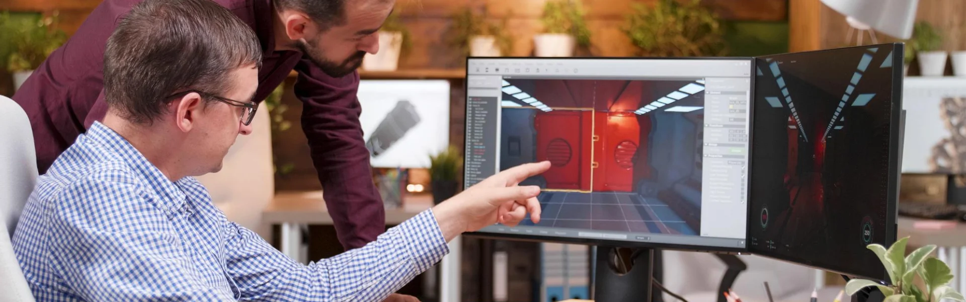 Two designers reviewing a 3D scene on a large monitor