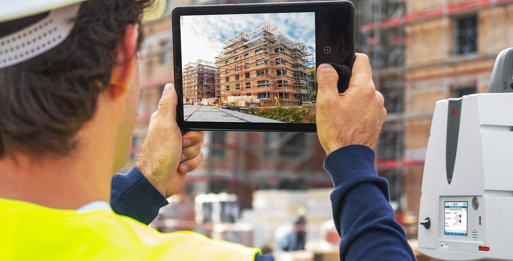 Site engineer using a tablet to capture reference photos during LiDAR scanning on a construction site
